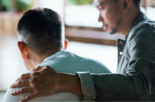 Person with arm around another in a comforting gesture.